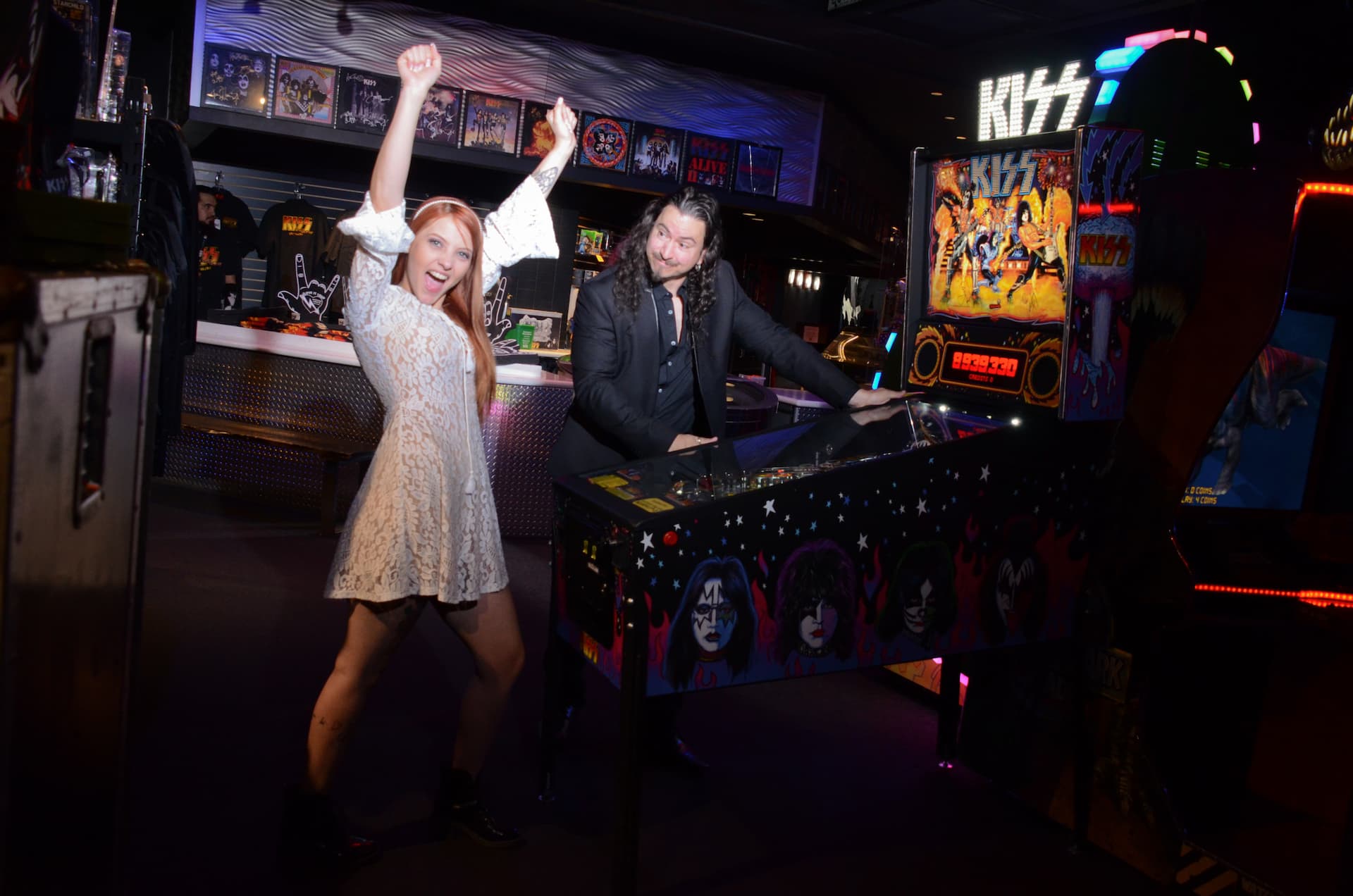 Bride And Groom Happy In Front Of Kiss Pinball Machine At Kiss Mini Golf.