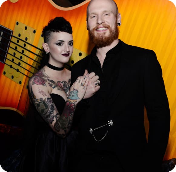 Bride And Groom Smiling In Front Of Large Orange Guitar Inside Of Kiss Mini Golf.